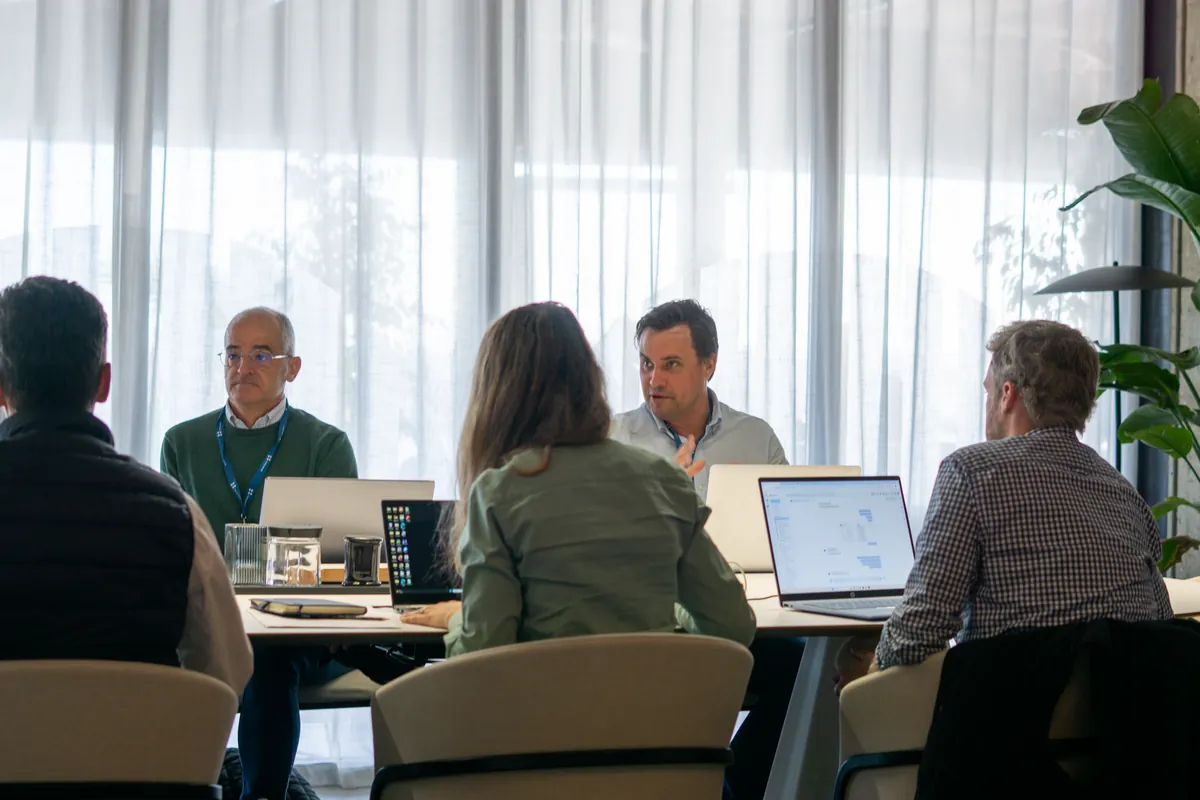 A small team working through an AI training session around a table with laptops