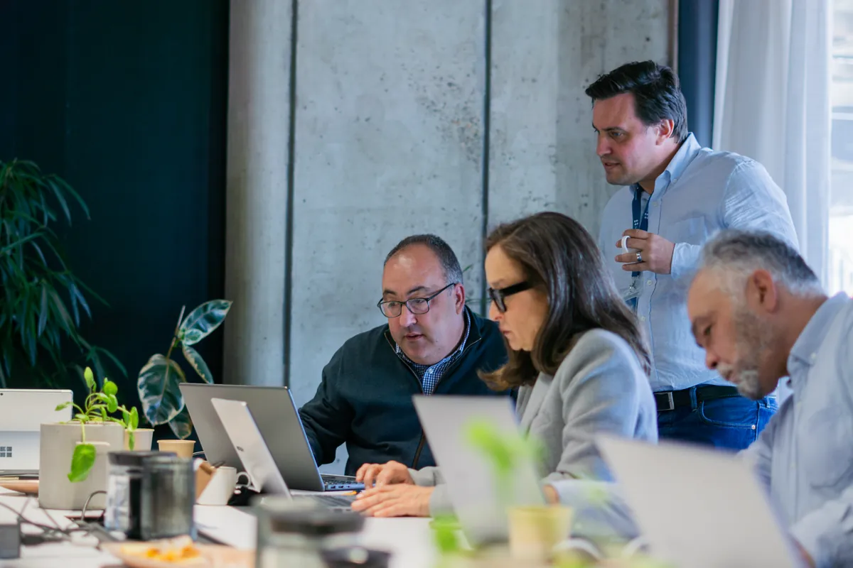 A team collaborating on laptops with hands-on support during an AI session